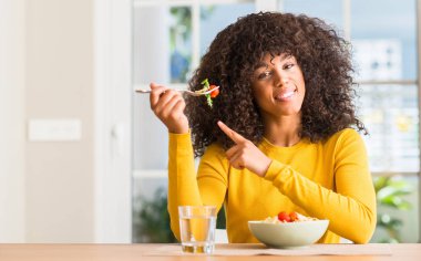 Afrikalı-Amerikalı kadın ev çok mutlu el ve parmak ile tarafına işaret makarna salata yemek