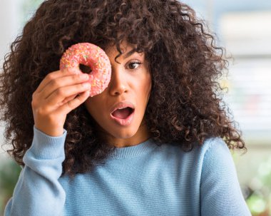 Çörek evde tutan Afrikalı-Amerikalı kadın korkmuş bir sürpriz yüz ile şok korkmuş ve heyecanlı korku ifadesi ile