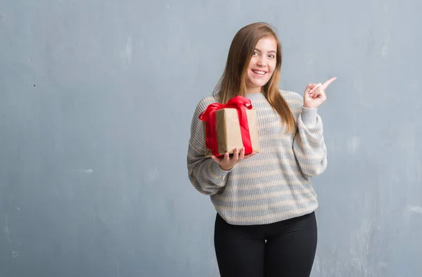 Mujer Adulta Joven Sobre Pared Grunge Gris Sosteniendo Regalo Muy —  Fotos de Stock