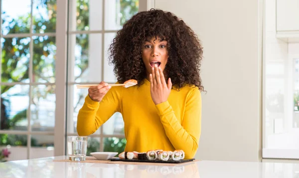 Africano Americano Mulher Comer Sushi Usando Pauzinhos Casa Cobrir Boca — Fotografia de Stock