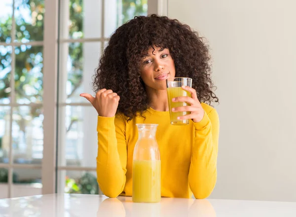非洲裔美国妇女饮用健康的果汁在家里指着手和手指与快乐的脸微笑 — 图库照片