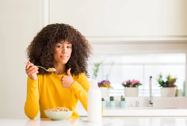 非洲裔美国妇女吃麦片和牛奶在家里高兴与大微笑做 拇指与手指 优秀的标志 — 图库照片