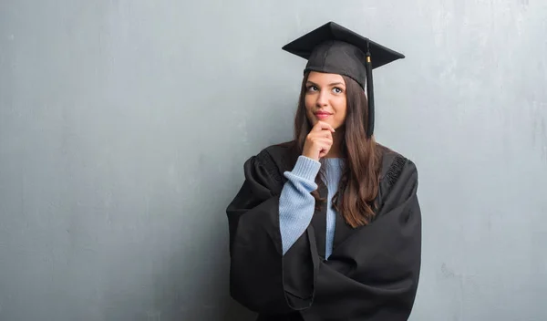 グランジ灰色の壁に関する質問は 非常に混乱して考え身に着けている大学院制服深刻な顔を考えての上の若いブルネットの女性 — ストック写真