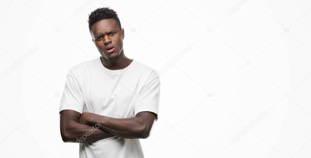 Young african american man wearing white t-shirt skeptic and nervous, disapproving expression on face with crossed arms. Negative person.