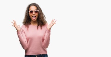 Güzel genç İspanyol kadın deli kutluyor ve silah ile başarı için heyecanlı çığlık kaldırdı ve açık gözleri hayret güneş gözlüğü takıyor. Kazanan kavramı