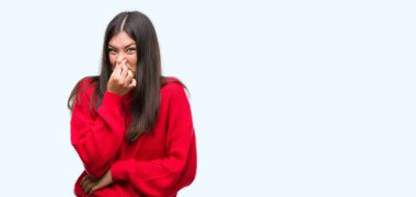 Kırmızı kazaklı bir şey pis ve iğrenç kokulu, dayanılmaz koku, holding nefes parmak ile burun üzerinde giyen genç güzel İspanyol. Kötü kokuyor kavramı.