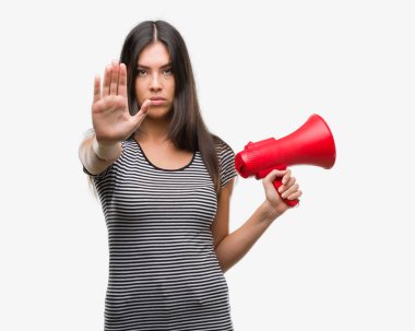 Açık eliyle dur işareti ile ciddi ve kendine güvenen ifade, savunma jest yapıyor megafon tutan genç İspanyol kadın