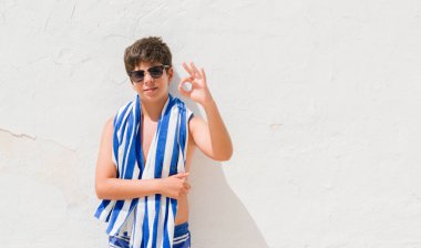 Tatil günlerinde parmak, mükemmel sembolü ile ok işareti yapıyor bir donanma havlu giyen genç çocuk