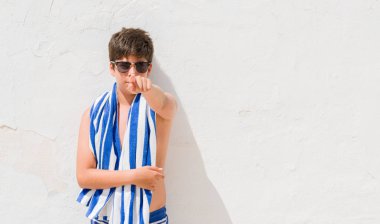 Genç çocuk kamera ve size parmak ile işaret bir donanma havlu giyen tatil günlerinde el işareti, pozitif ve kendinden emin bir jest ön