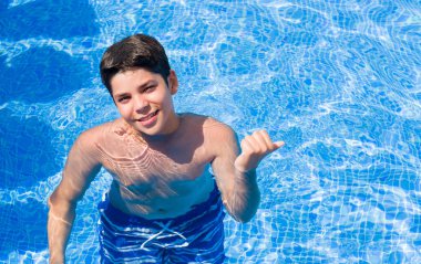 İşaret ve başparmak kadar mutlu yüz gülümseyen tarafı ile gösterilen plajda yüzme havuzunda tatil günlerinde genç çocuk