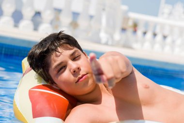 Genç çocuk yüzme havuzu kamera ve size parmak ile işaret sahilde tatil günleri pad üzerinde el işareti, pozitif ve kendinden emin bir jest ön