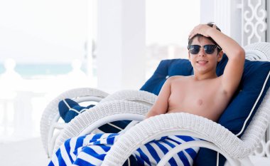 Tatil günlerinde kafasına, el ile vurguladı sandalye üzerinde oturan genç çocuk şok utanç ve sürpriz suratla, öfkeli ve sinirli. Korku ve hata için üzgün.