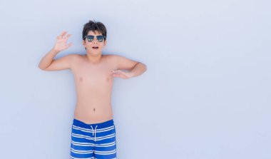 Duvarın bir sürpriz yüz, korkuyor ve heyecanlı korku ifadesi ile şok korkmuş üzerinden ayakta tatil günlerinde genç çocuk