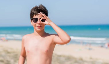 Mutlu yüz el parmaklarının arasından seyir göz üzerinde ok işaretiyle yapıyor gülümseyen ile sahilde tatil günlerinde genç çocuk