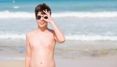 Mutlu yüz el parmaklarının arasından seyir göz üzerinde ok işaretiyle yapıyor gülümseyen ile sahilde tatil günlerinde genç çocuk