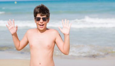 Kocaman bir gülümseme ile çığlık zaferini kutluyor ve ellerini kaldırdı beach çok mutlu ve heyecanlı, kazanan ifade, tatil günlerinde genç çocuk