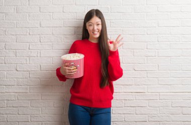 Genç Çinli kadın parmakları, mükemmel sembolü olan ok işareti yapıyor pop Mısır yeme tuğla duvarın üzerinden