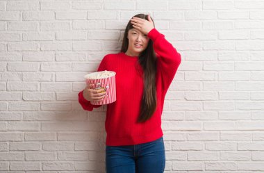 Pop corn kafasına, el ile vurguladı yeme tuğla duvarın üzerinden Genç Çinli kadın şok utanç ve sürpriz suratla, öfkeli ve sinirli. Korku ve hata için üzgün.