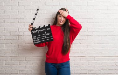 Baş, el ile vurguladı fıçı tahtası holding beyaz tuğla duvarın üzerinden Genç Çinli kadın şok utanç ve sürpriz suratla, öfkeli ve sinirli. Korku ve hata için üzgün.