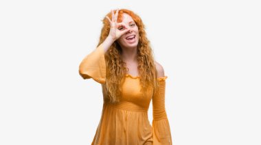 Genç Kızıl saçlı kadının gülümseyen, parmakları ile mutlu yüz üzerinden seyir göz el ile ok jest yapması.