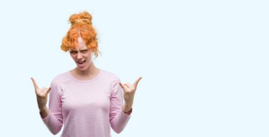 Deli ifade rock simge elle yapıyor ile bağırarak genç Kızıl saçlı kadın. Müzik yıldızı. Ağır kavramı.