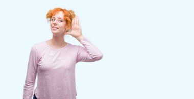 Bir işitme söylenti ya da dedikodu için dinleme kulak üzerinde el ile gülümseyen genç Kızıl saçlı kadın. Sağırlık kavramı.