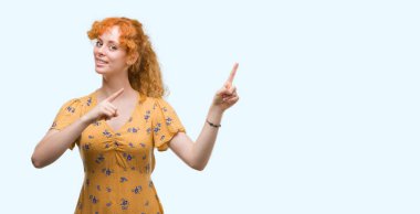 Gülümseyen ve iki ile işaret kamera bakarak genç Kızıl saçlı kadın eller ve yan parmak.