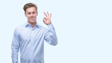 Parmak, mükemmel sembolü ile ok işareti yapan genç yakışıklı sarışın erkek