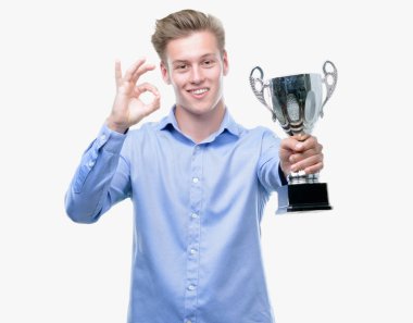 Genç yakışıklı sarışın adam parmak, mükemmel sembolü ile ok işareti yapıyor bir kupa holding