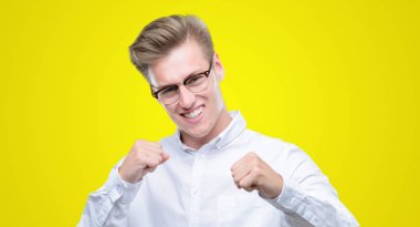 Gülümseyen ve başarı için çığlık genç sarışın yakışıklı çok mutlu ve heyecanlı kaldırdı, silah ile kazanan jest yapıyor. Kutlama kavramı.