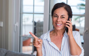 El ve parmak ile tarafına işaret çok mutlu Smartphone kullanan orta yaşlı kadın