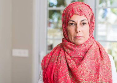 Acımak yüz düşünme ciddi kendine güvenen bir ifade ile hijab giyen orta yaşlı Müslüman kadın