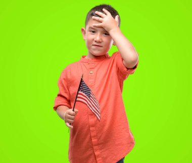 Amerika Birleşik Devletleri bayrağı ile vurguladı kafasına, utanç ve sürpriz yüz, öfkeli ve sinirli ile şok el holding koyu saçlı küçük çocuk. Korku ve hata için üzgün.
