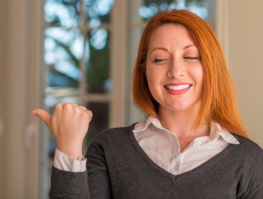 Kızıl saçlı kadın evde el ve parmak ile mutlu yüz gülümseyen ile yukarı dönük