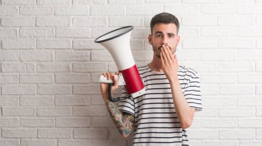 Sessizlik, gizli kavramı megafon kapak ağız hata, korku, ifade için utanç ile şok eliyle tutan genç yetişkin adam korkuttu