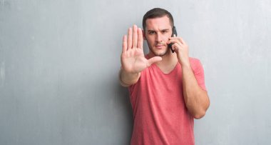 Genç beyaz adam açık eliyle dur işareti ile ciddi ve kendine güvenen ifade, savunma jest yapıyor Evet gri grunge duvarın üzerinden