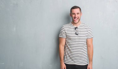 Beyaz delikanlı dilini gri grunge duvarın üzerinden out komik ifade ile mutlu. Duygu kavramı.