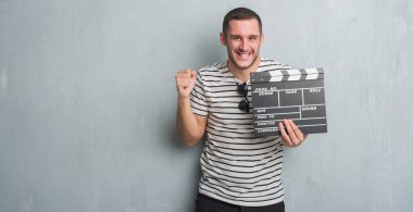 Duygu tezahürat Genç beyaz adam gurur çığlık ve zafer ve başarı çok heyecanlı, kutluyor film fıçı tahtası tutan gri grunge duvarın üzerinden