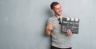 Beyaz delikanlı film fıçı tahtası çok mutlu el ve parmak ile işaret tutan gri grunge duvarın üzerinden