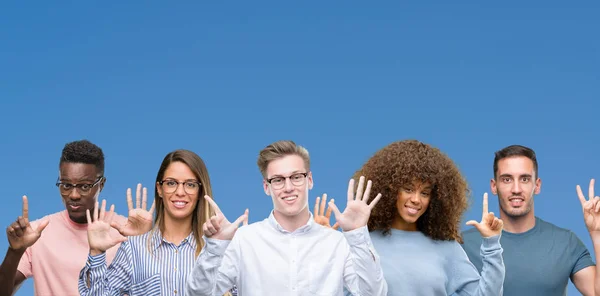 小组朋友的组合在蓝色背景显示并且指向与手指数字七 当微笑自信和愉快时 — 图库照片