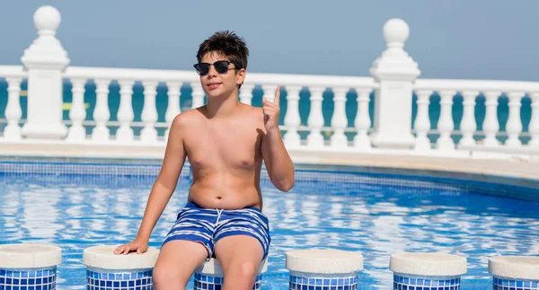 Genç çocuk yüzme, tatilde plajda bir fikirle sürpriz havuz veya gülen yüz, bir numara ile işaret parmağı soru