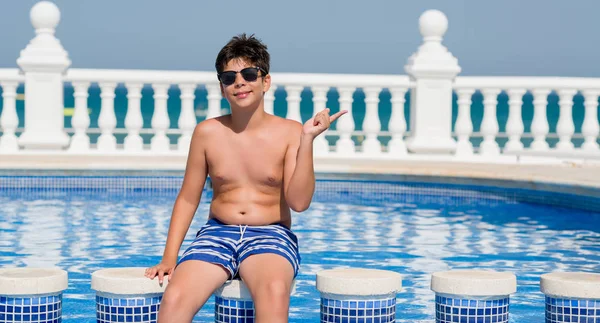 Genç çocuk tatilde plajda el ve parmak ile tarafına işaret çok mutlu yüzme havuzunda