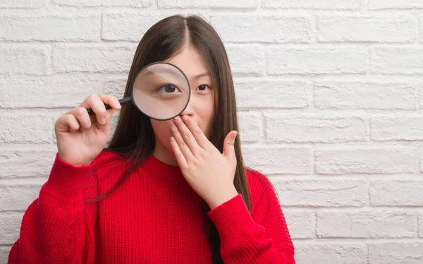 Young Chinese Woman Brick Wall Looking Magnifying Glass Cover Mouth — Stock Photo, Image