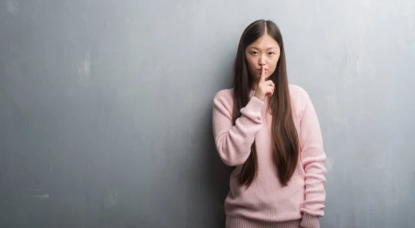 在灰色墙壁上的年轻中国妇女要求用手指在嘴唇安静 沉默和秘密概念 — 图库照片