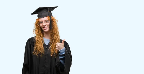 身に着けている赤毛の若い学生女性笑顔の サイン 優秀な兆候を親指をやって幸せな制服を卒業 — ストック写真