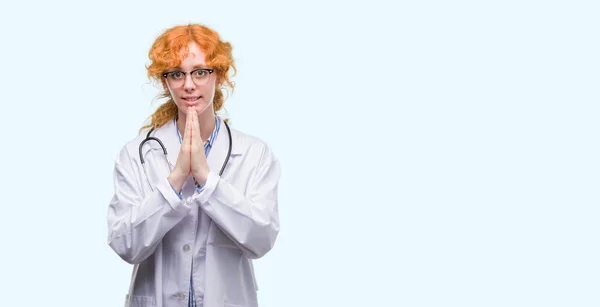 Jovem Ruiva Vestindo Uniforme Médico Orando Com Mãos Juntas Pedindo — Fotografia de Stock