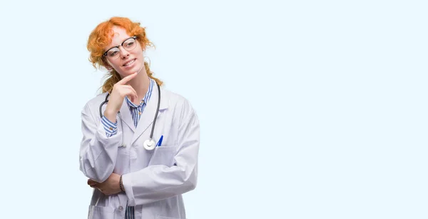Unga Rödhårig Kvinna Bär Läkare Uniform Med Hand Hakan Funderar — Stockfoto