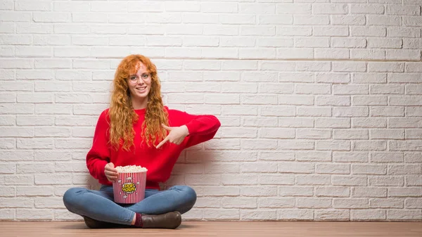 Unga Rödhårig Kvinna Sitter Över Tegelvägg Äta Popcorn Väldigt Glad — Stockfoto