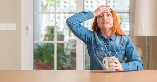 Rødhåret Kvinde Holder Kop Kaffe Stresset Med Hånd Hoved Chokeret - Stock-foto