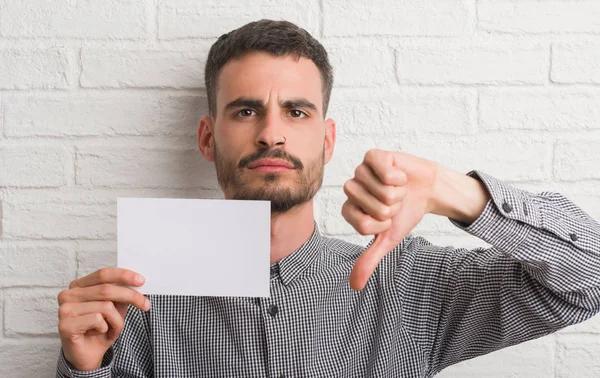 Ung Vuxen Man Över Tegelvägg Holding Blankt Papper Med Arga — Stockfoto